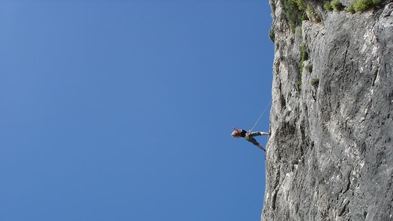Un homme qui gravit une montagne à l'aide d'une corde. 