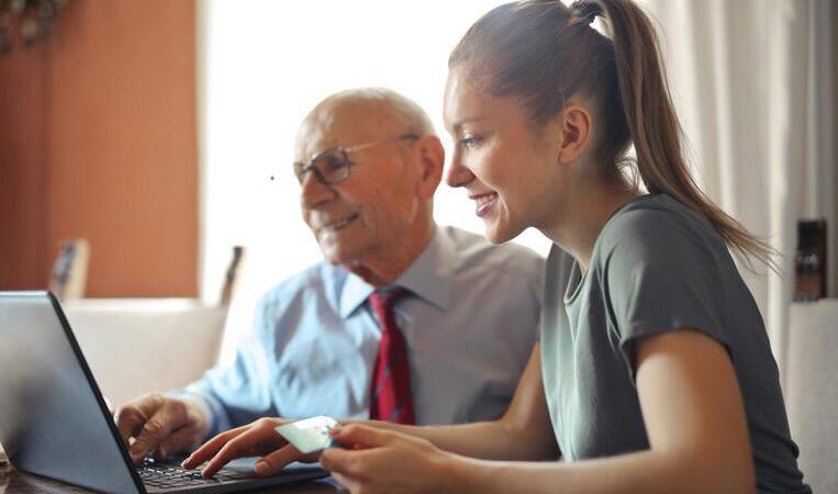 Ein älterer Herr und eine junge Damen sitzen vor dem Laptop und unterhalten sich über Anlagefonds.